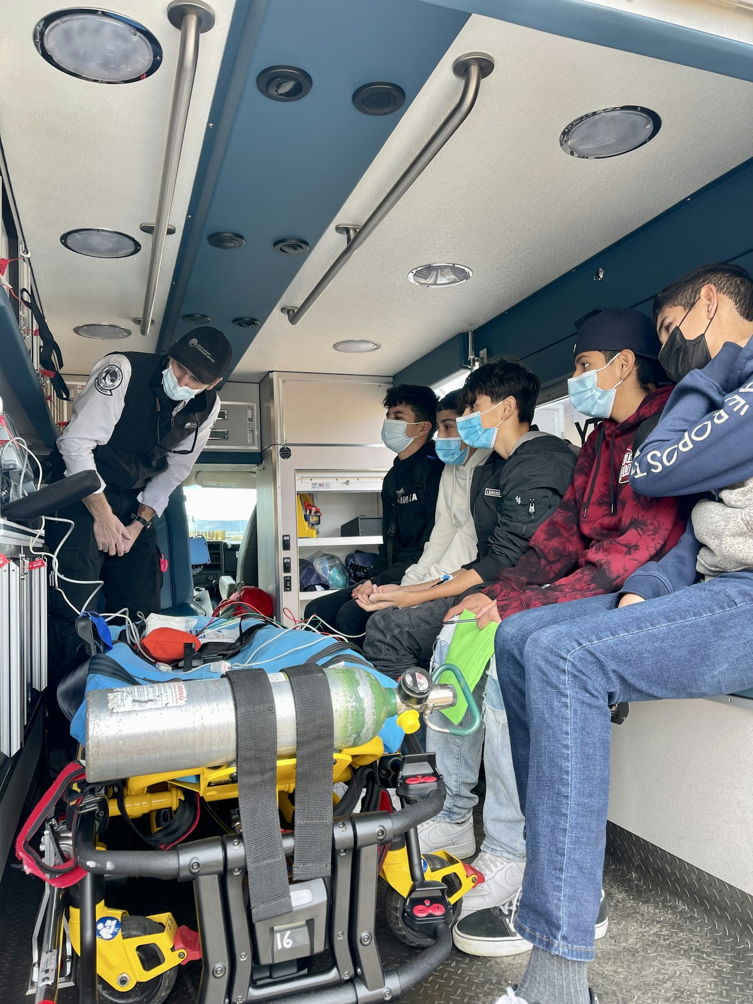 Paramedic in ambulance, showing equipment to high school students.