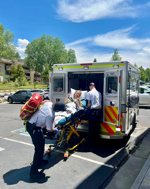 A person on a stretcher being placed into an ambulance by emergency responders.