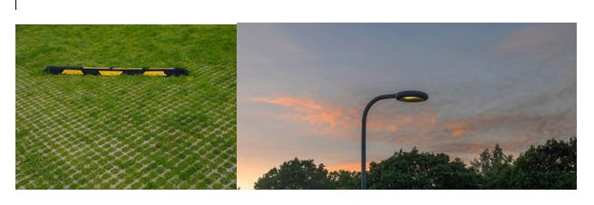 A grassy area with a black and yellow speed bump, and a streetlight against a sunset sky.