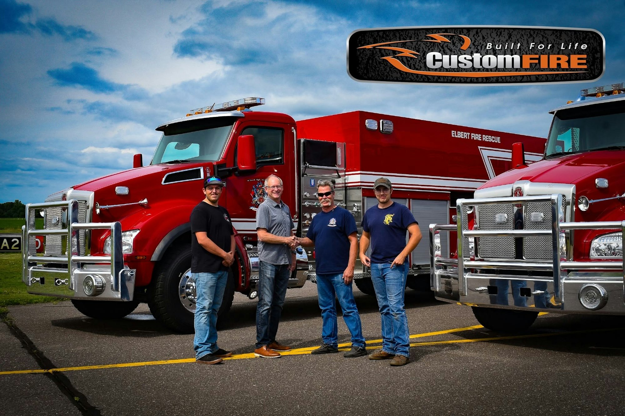 Four individuals stand beside two red fire trucks, shaking hands in front of a logo that reads "Custom FIRE."