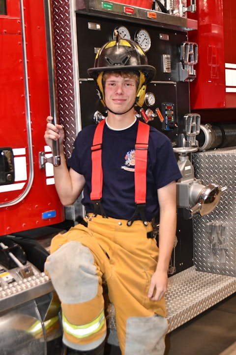 Person in firefighting gear sitting in a fire truck.
