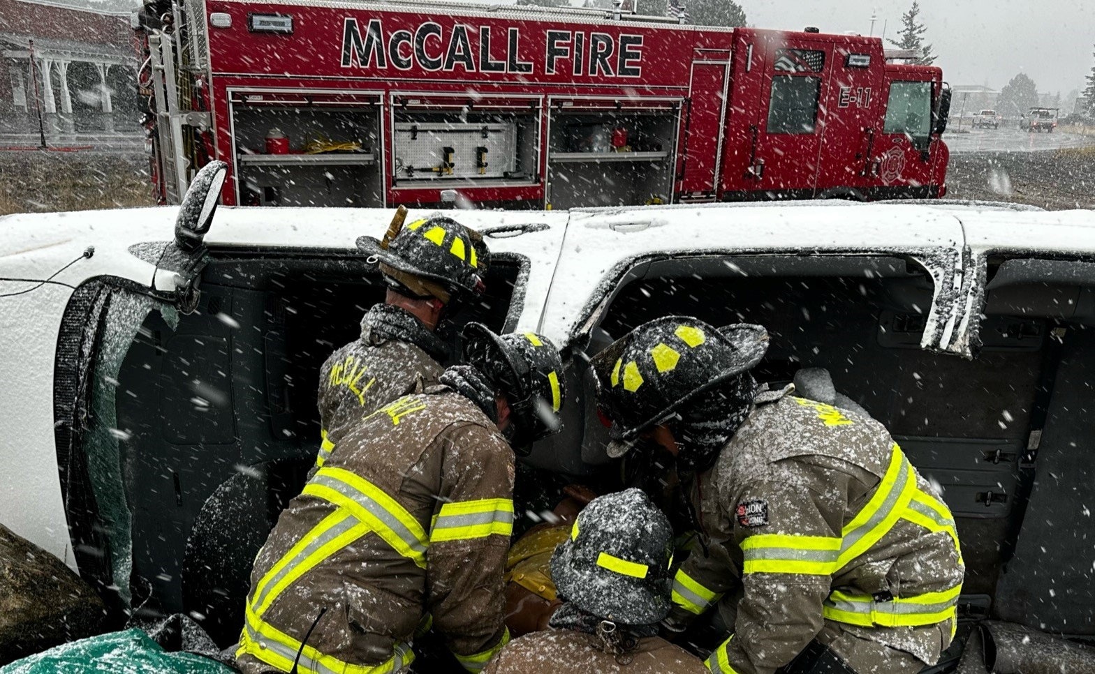 Firefighters are responding to an incident involving an overturned vehicle in snowy conditions.