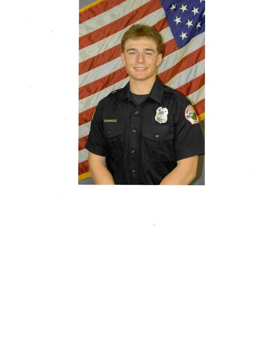 A person in a navy uniform poses in front of a U.S. flag.