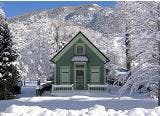 A green house surrounded by snow-covered trees and mountains.