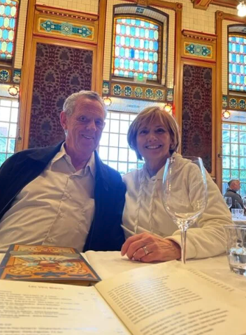 Two people smiling at a table with menus, inside a room with stained glass windows.