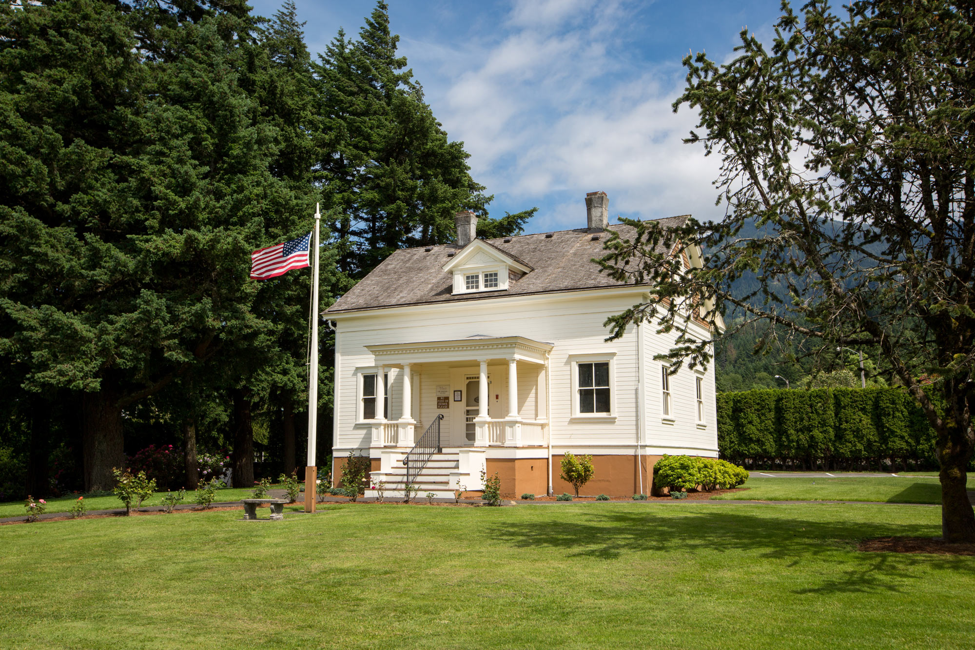 May contain: grass, plant, lawn, tree, bench, furniture, architecture, building, housing, and flag
