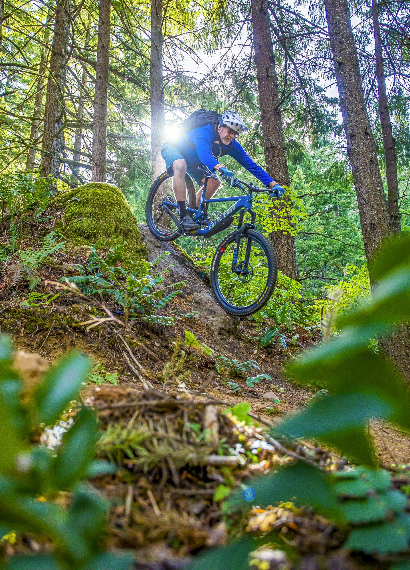 ©RHALLMAN; A mountain biker riding through a lush forest.