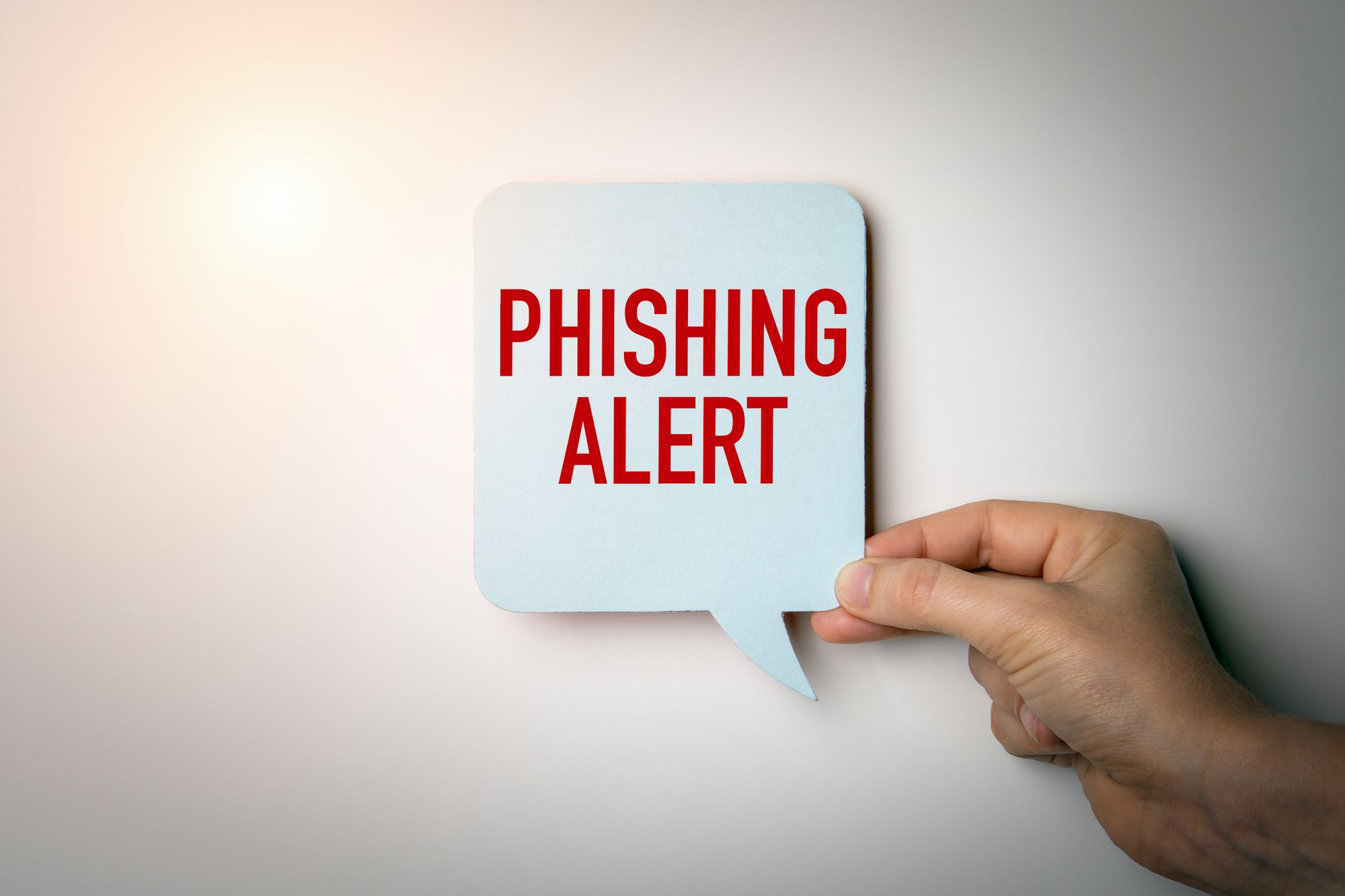 A hand holds a speech bubble with the words "PHISHING ALERT" in red text.