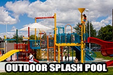 Colorful outdoor splash pool with slides and play structures, under a sunny sky.