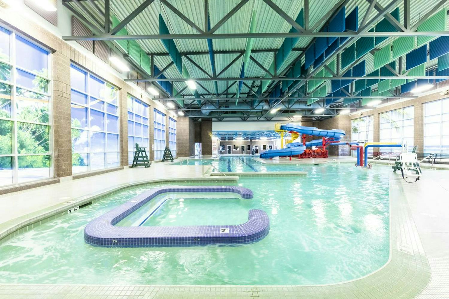 Indoor swimming pool with a slide, windows, and a kiddie pool area.
