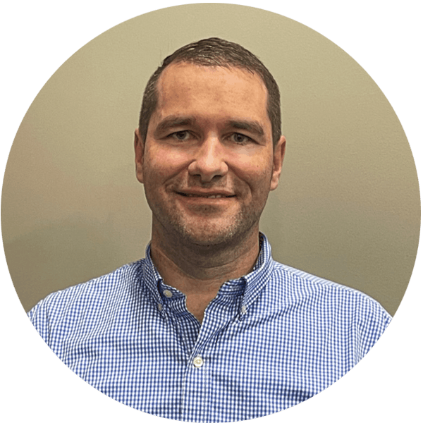 A smiling person wearing a checkered shirt, with a plain background.