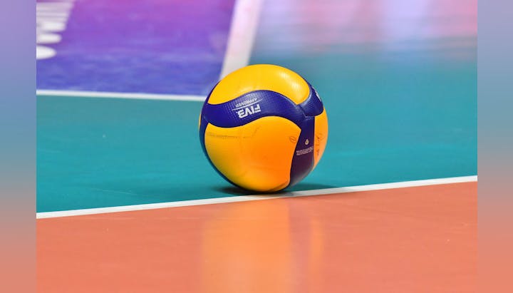 A volleyball on a colorful court, possibly during a break in a match.