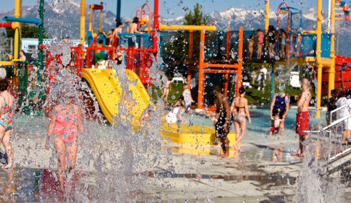 A colorful splash pad with children playing and water features.