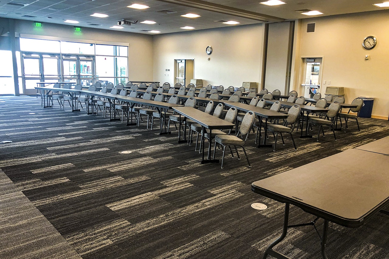 Empty conference room with tables, chairs, and a clock on the wall.