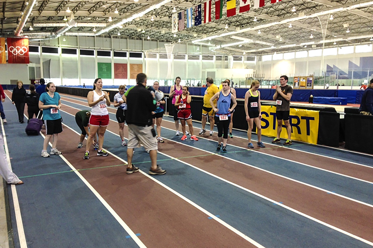 Runners at the start line of an indoor track event.