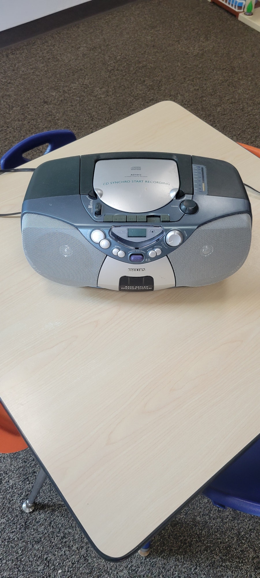A portable CD player with speakers on a wooden table, rotated sideways.