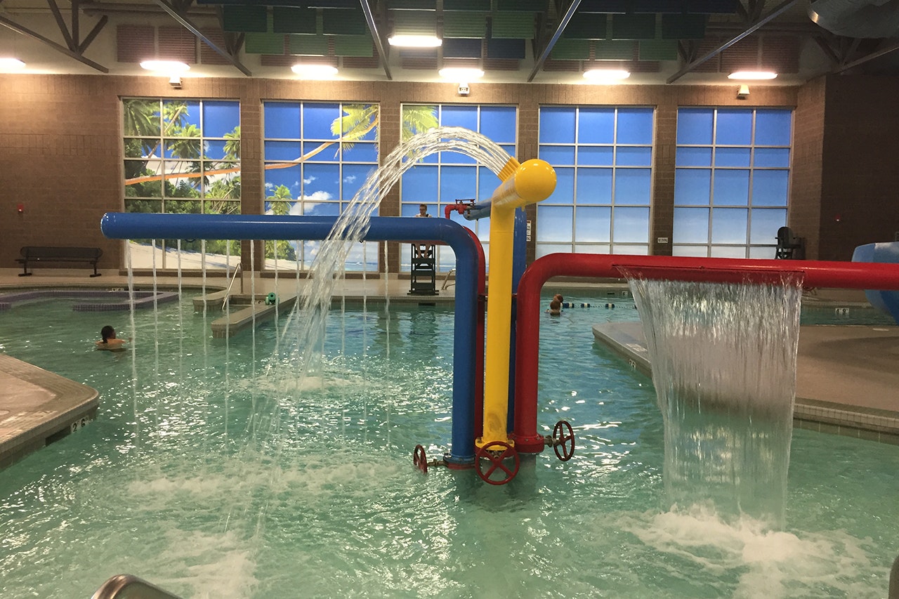 Indoor pool with water features and people swimming.