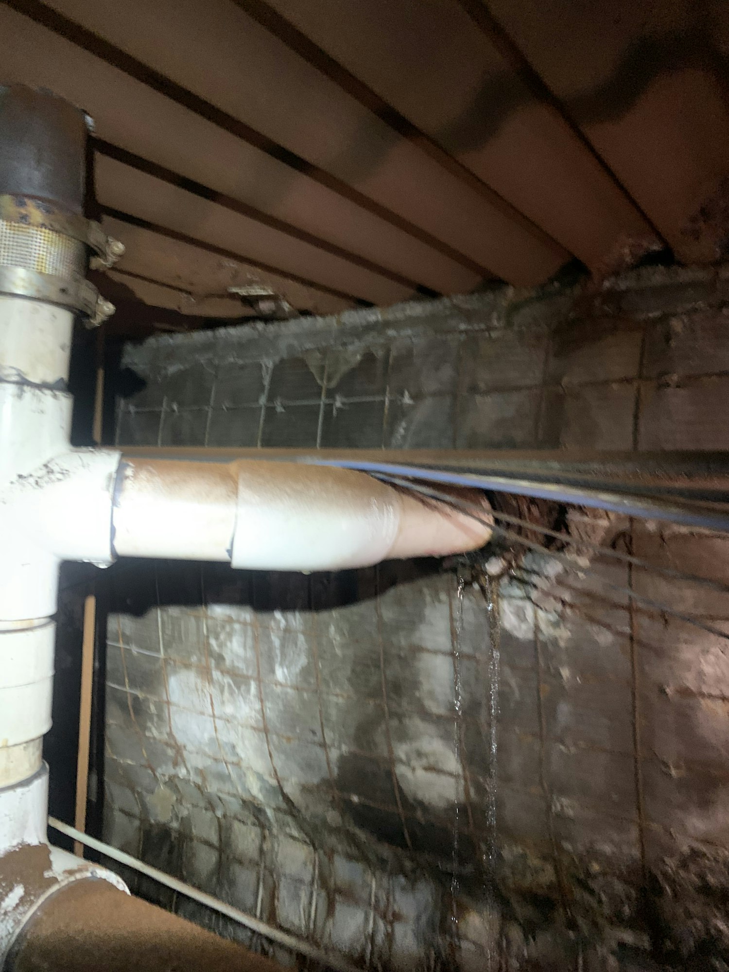 Pipes and beams in a dark, industrial area with visible rust and grime.