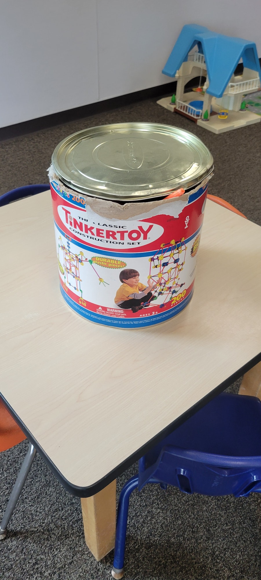 A Tinkertoy set on a desk, photo taken at an angle, with toppled toy furniture in the background.