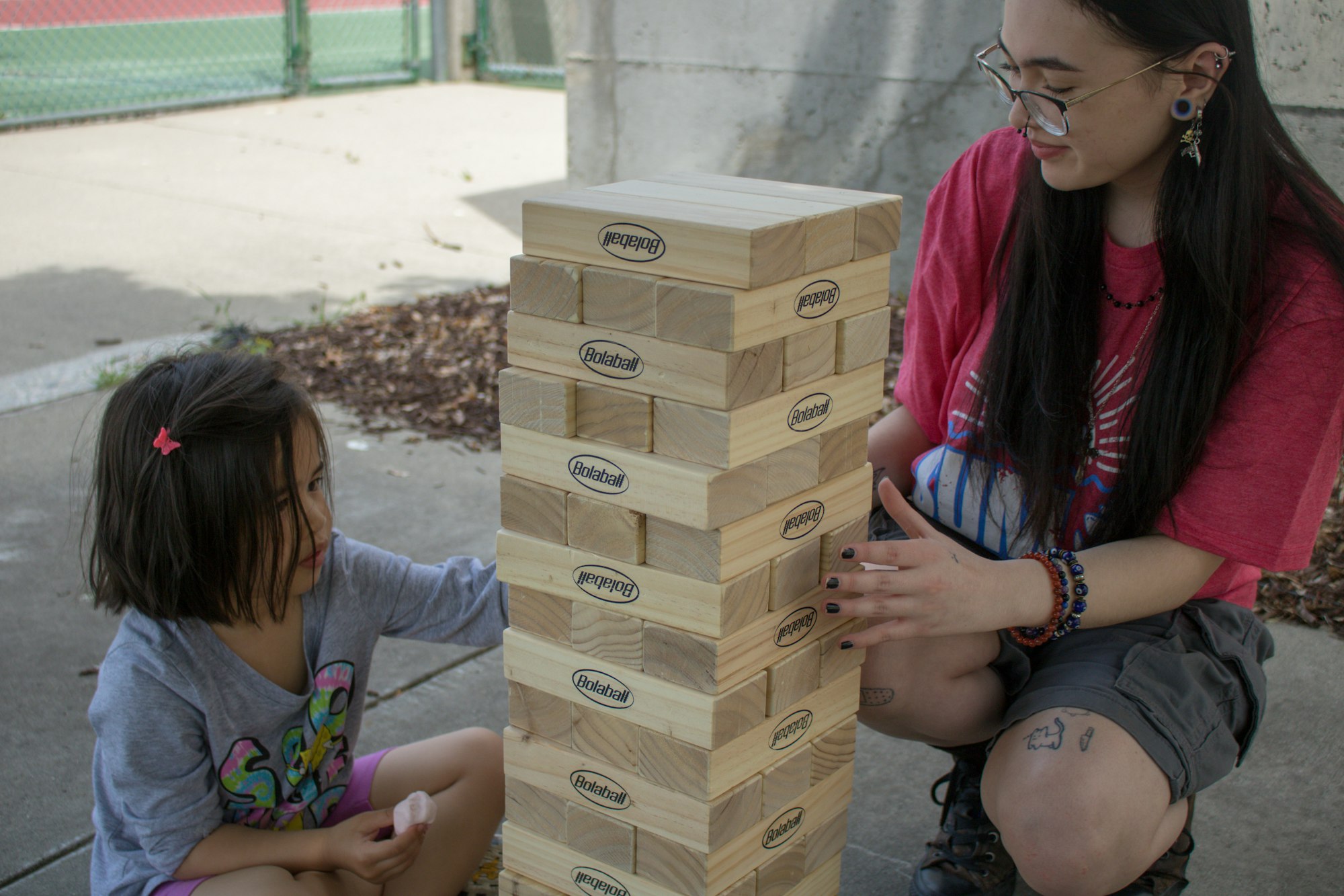 Two people playing a giant Jenga game outdoors.