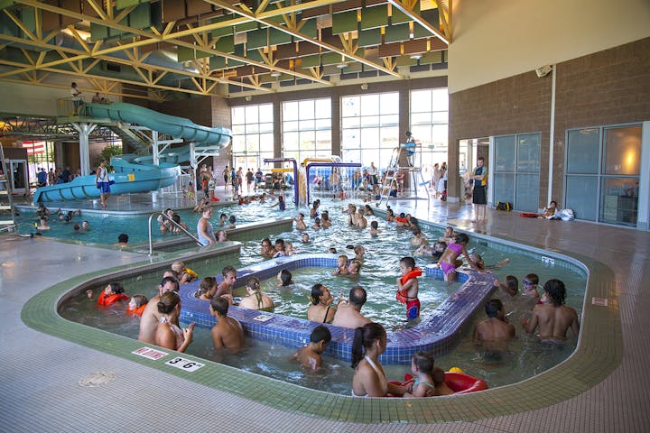 Indoor pool with swimmers, a water slide, and a lazy river.