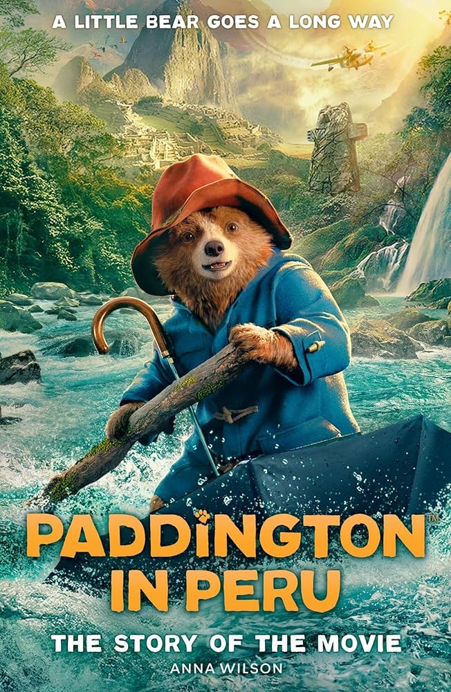 Bear in a blue coat and red hat paddling through water, jungle background. Text: "Paddington in Peru: The Story of the Movie" by Anna Wilson.