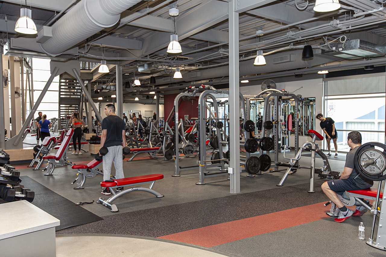 A gym with various workout equipment and several people exercising.