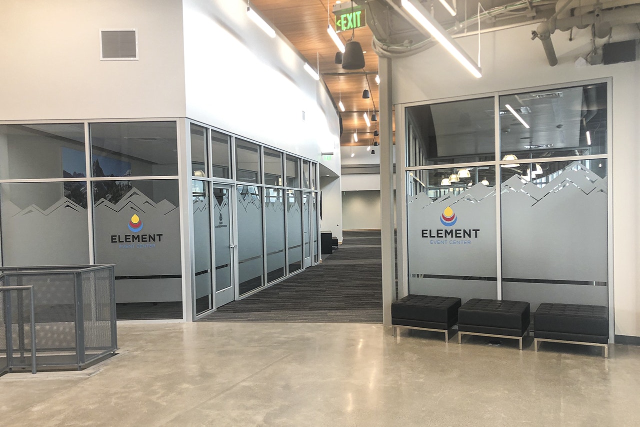 Modern interior with glass doors of "ELEMENT EVENT CENTER", benches, and a polished concrete floor.