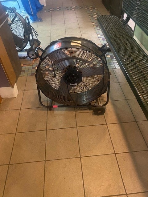 A large floor fan on tiled flooring, likely for air circulation or drying purposes.