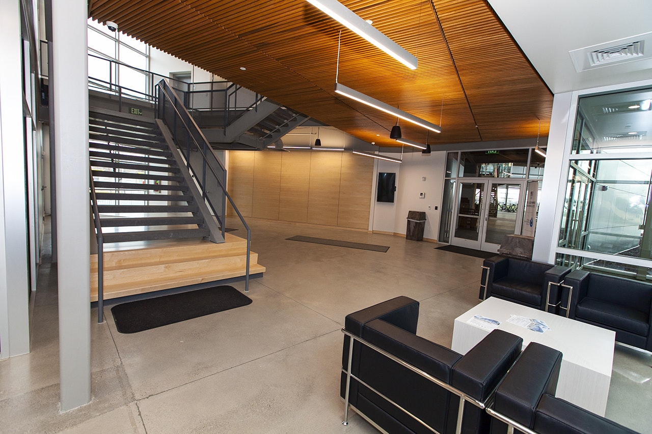 Modern interior with stairs, wood ceiling, seating area, and glass doors.