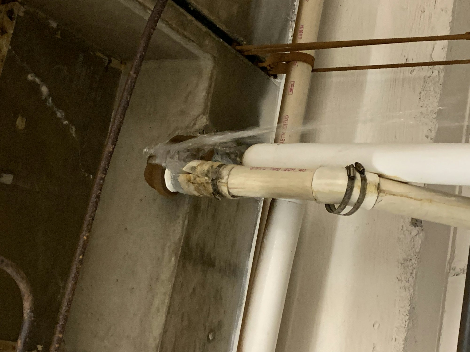 Water spraying from a leaking pipe joint on a ceiling.