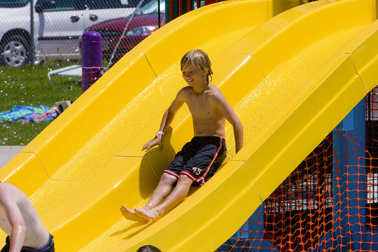 A child slides down a bright yellow water slide, appearing joyful.