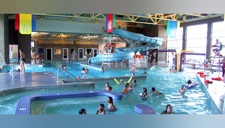 Indoor pool with swimmers, water slides, and lifeguards—people enjoying water activities.