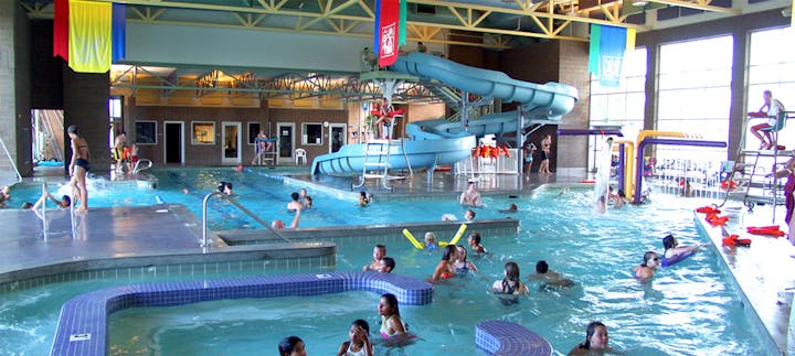 Indoor pool with swimmers, water slides, and lifeguards—people enjoying water activities.