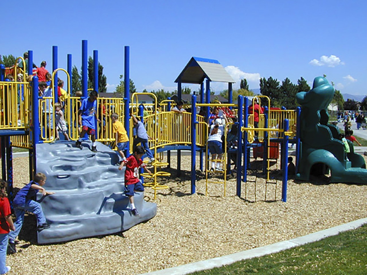 A colorful playground with climbing structures and children playing under a sunny sky.