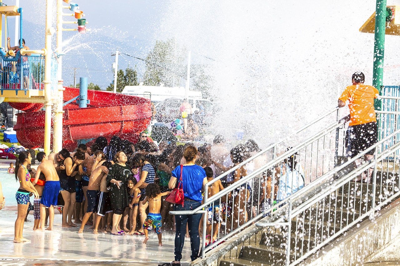 People enjoying a water splash at a water park on a sunny day.