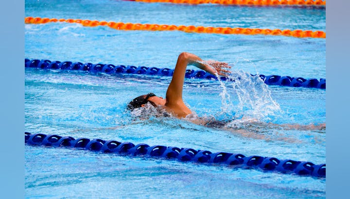A swimmer in mid-stroke in a pool with blue and orange lane dividers.
