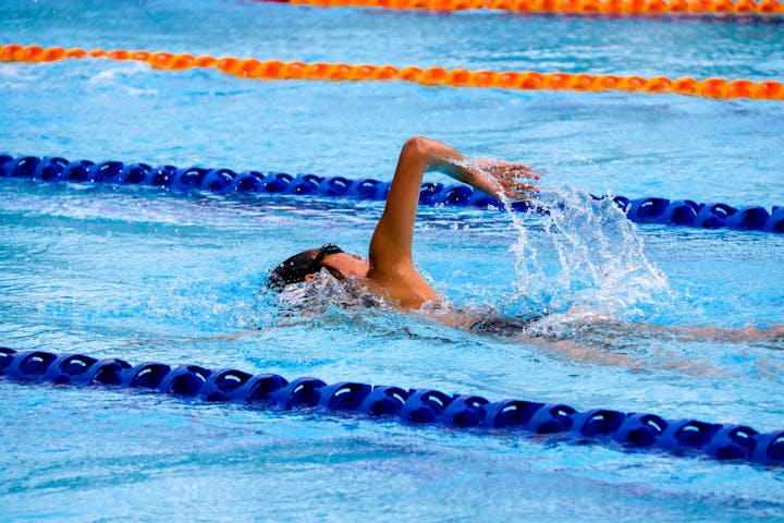 A swimmer in mid-stroke in a pool with blue and orange lane dividers.