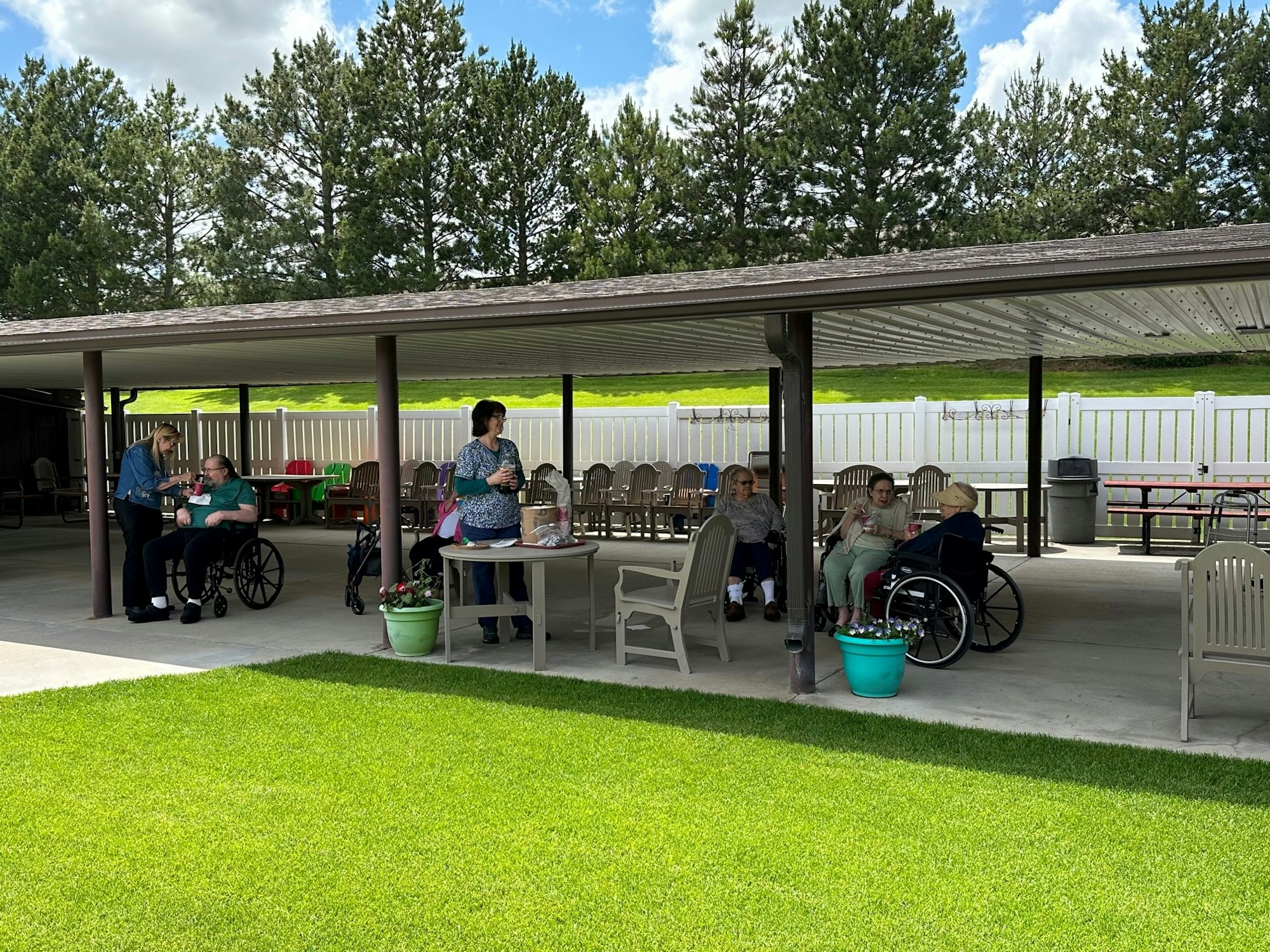 May contain: architecture, building, outdoors, shelter, grass, plant, person, clothing, footwear, shoe, furniture, desk, table, hat, chair, accessories, bag, handbag, nature, and park