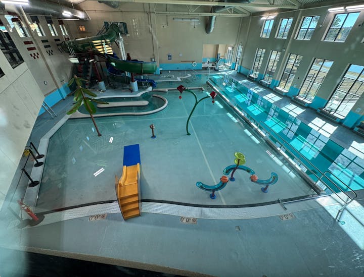 Indoor pool with a water slide, splash features, and a shallow play area.