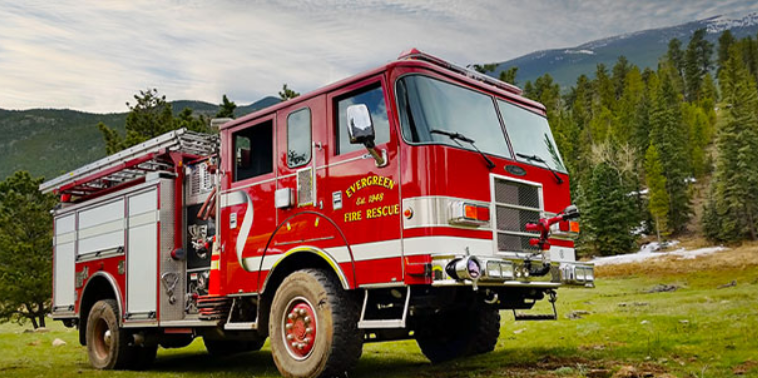 A red fire truck from Evergreen Fire Rescue, parked in a scenic area with mountains and trees in the background.