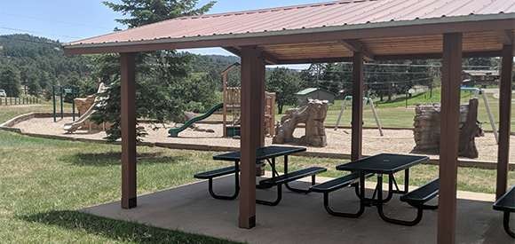 A playground with slides and picnic tables under a shelter.