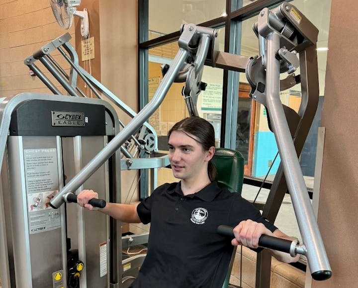 A person using a chest press machine at the gym.