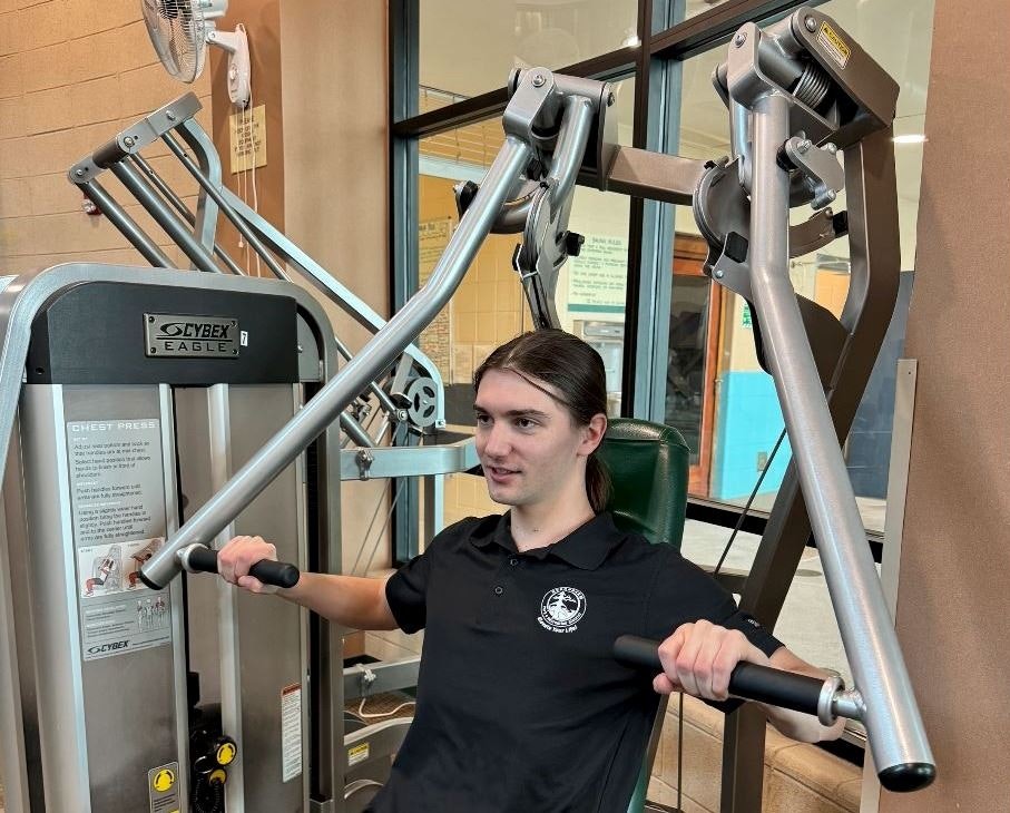 A person using a chest press machine at the gym.