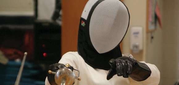 A person in fencing gear holding a fencing foil.