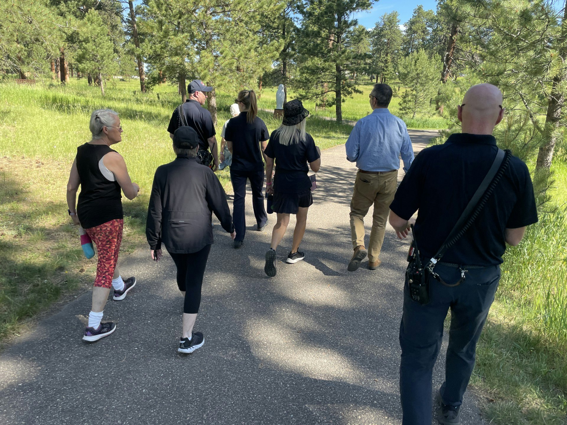 A group of people walking on a path through a forested area, enjoying a day outdoors.