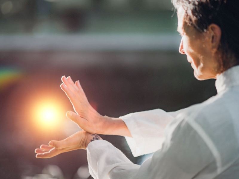 Person in white practicing tai chi in sunlight.