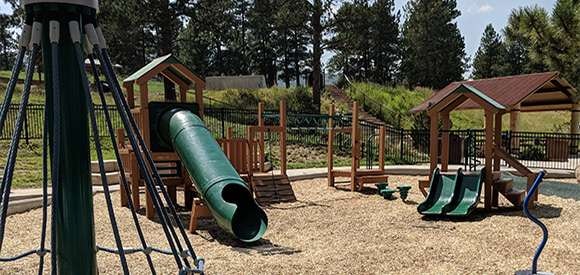 Playground with slides, swings, and climbing structures on a sunny day.