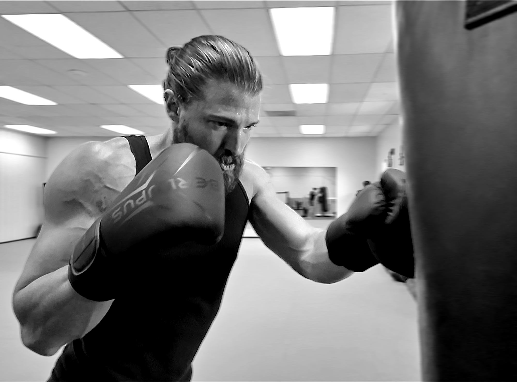 A person with boxing gloves punches a heavy bag in a gym.