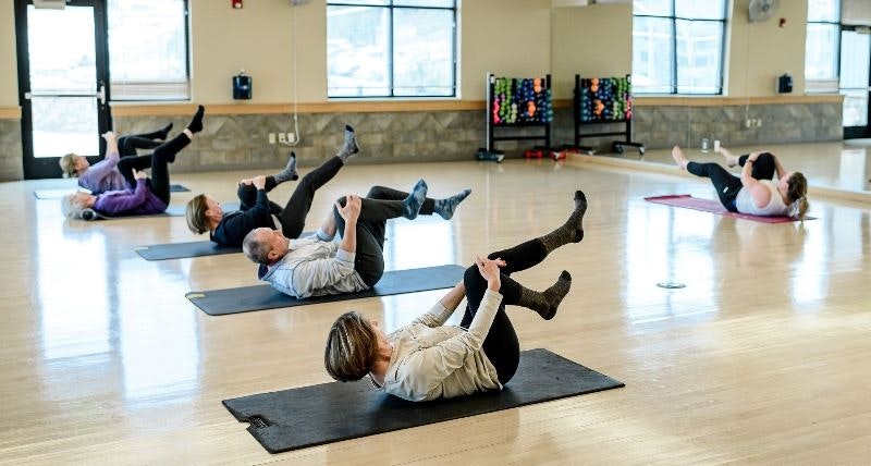 People exercising on mats in a gym.